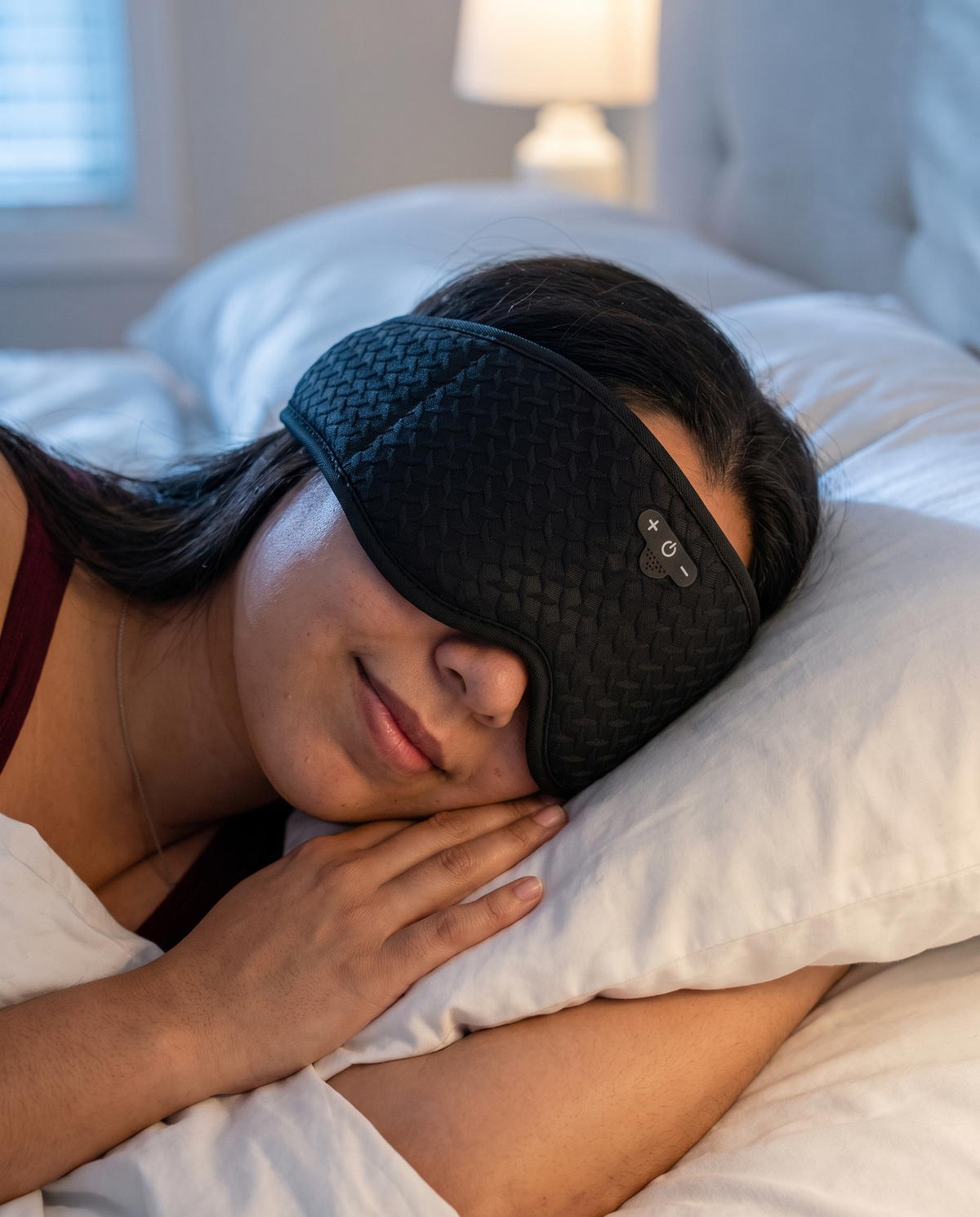 Person sleeping peacefully on their side wearing the NovaDream sleep mask, soft warm bedroom lighting